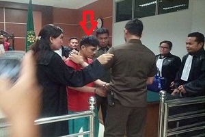 Terdakwa Wardiaman Zebua , dikawal ketat . tampak petugas penjaga tahanan berdiri memasukkan borgol ketangan Wardiaman. foto / as (potretkepri.com) 